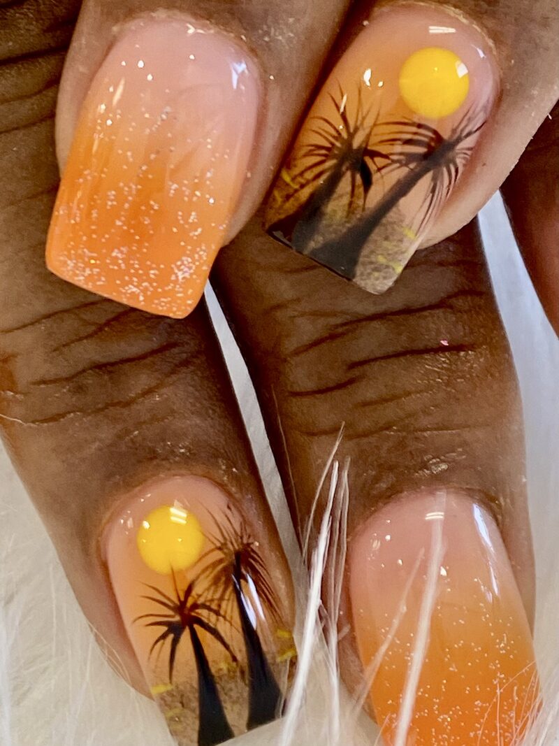 Orange sunset nails with palm tree silhouette and glitter ombre
