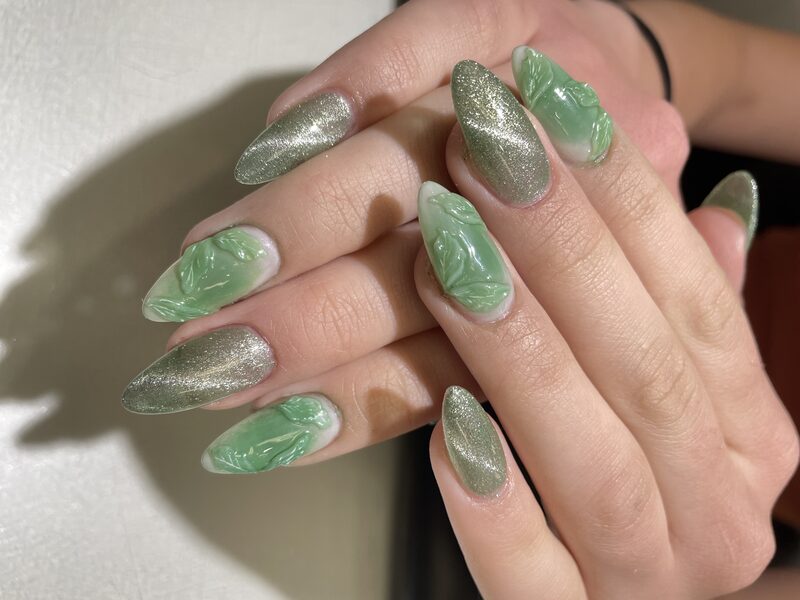 Green chrome stiletto nails with embossed leaf design